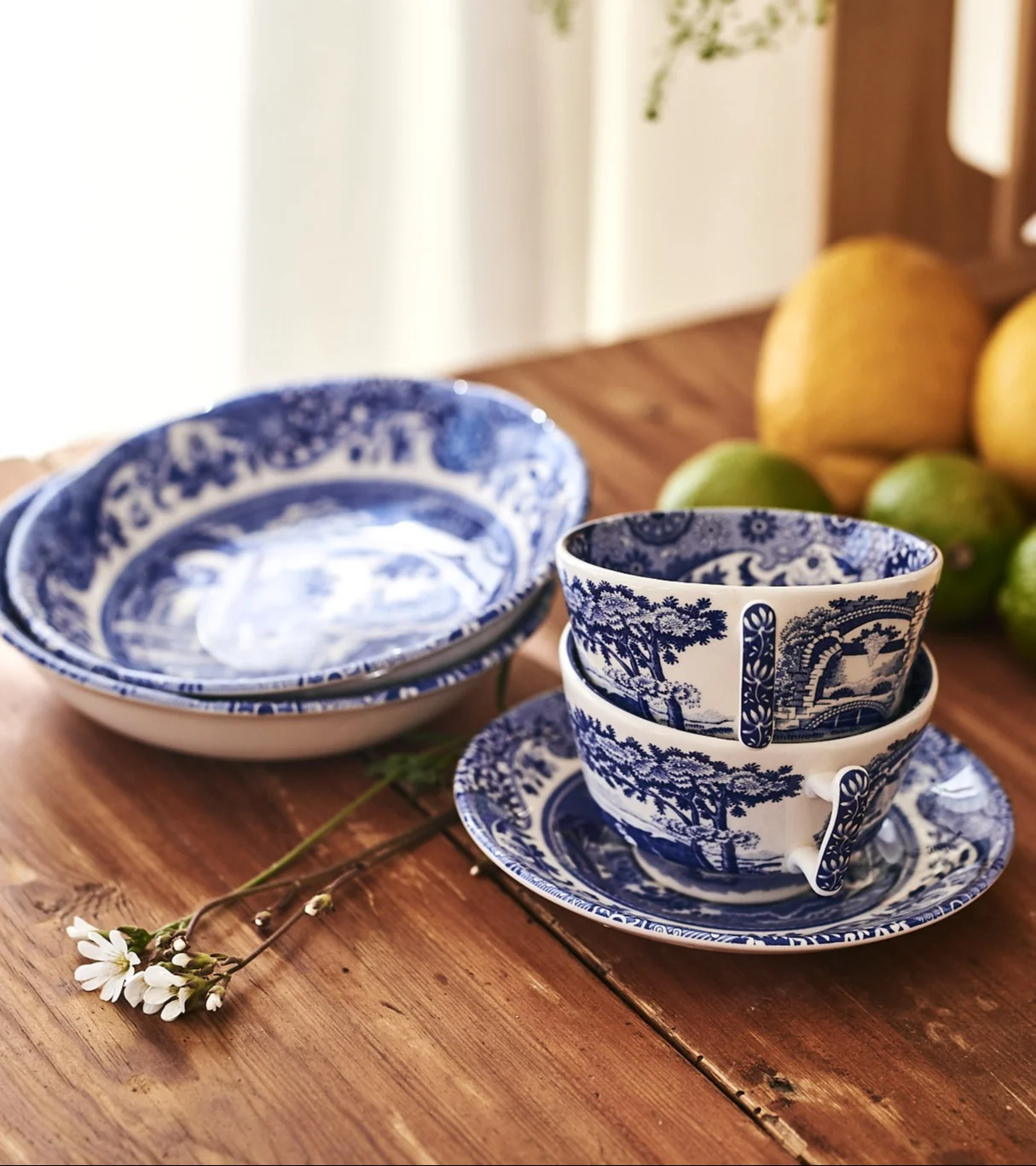 Blau-weiß gemustertes Keramikgeschirr, darunter Schalen, Teetassen und Untertassen, auf einem Holztisch.