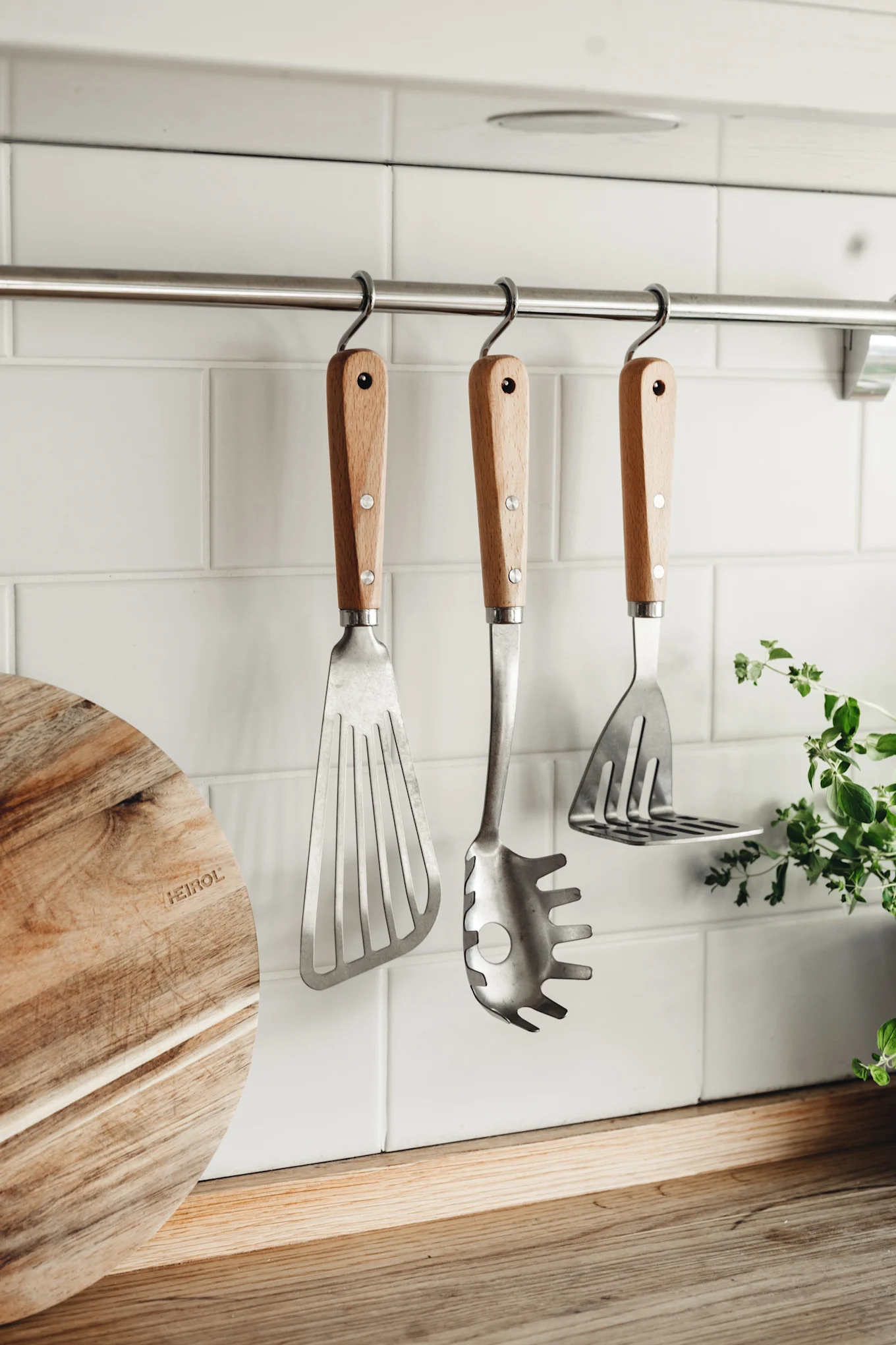 Pfannenwender, Kelle und Kartoffelstampfer von Heirol hängen an einer Stange in der Küche.