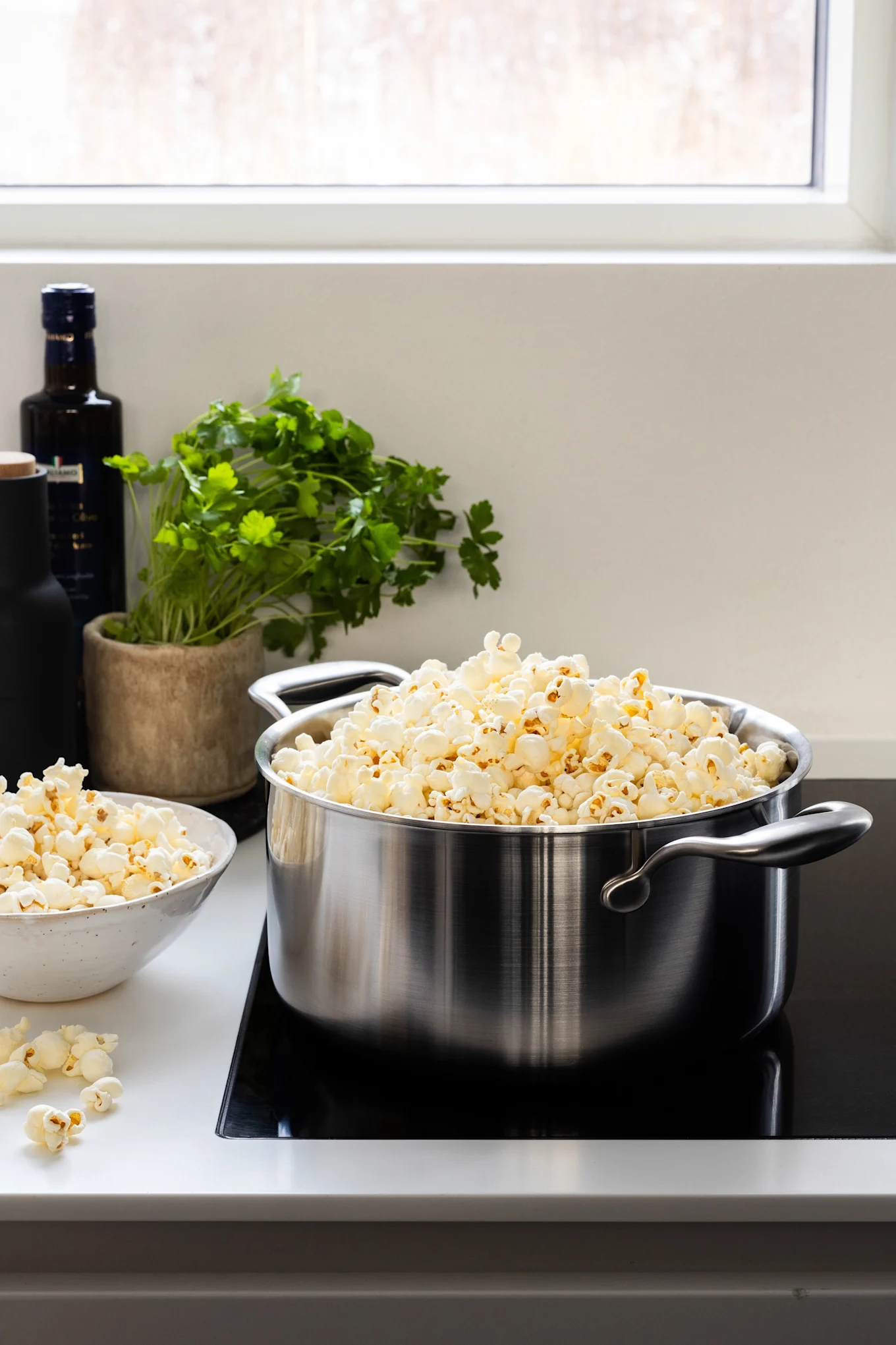 Der Kochtopf mit Ausgießdeckel von Wilfa steht mit fertigem Popcorn auf einer Herdplatte.