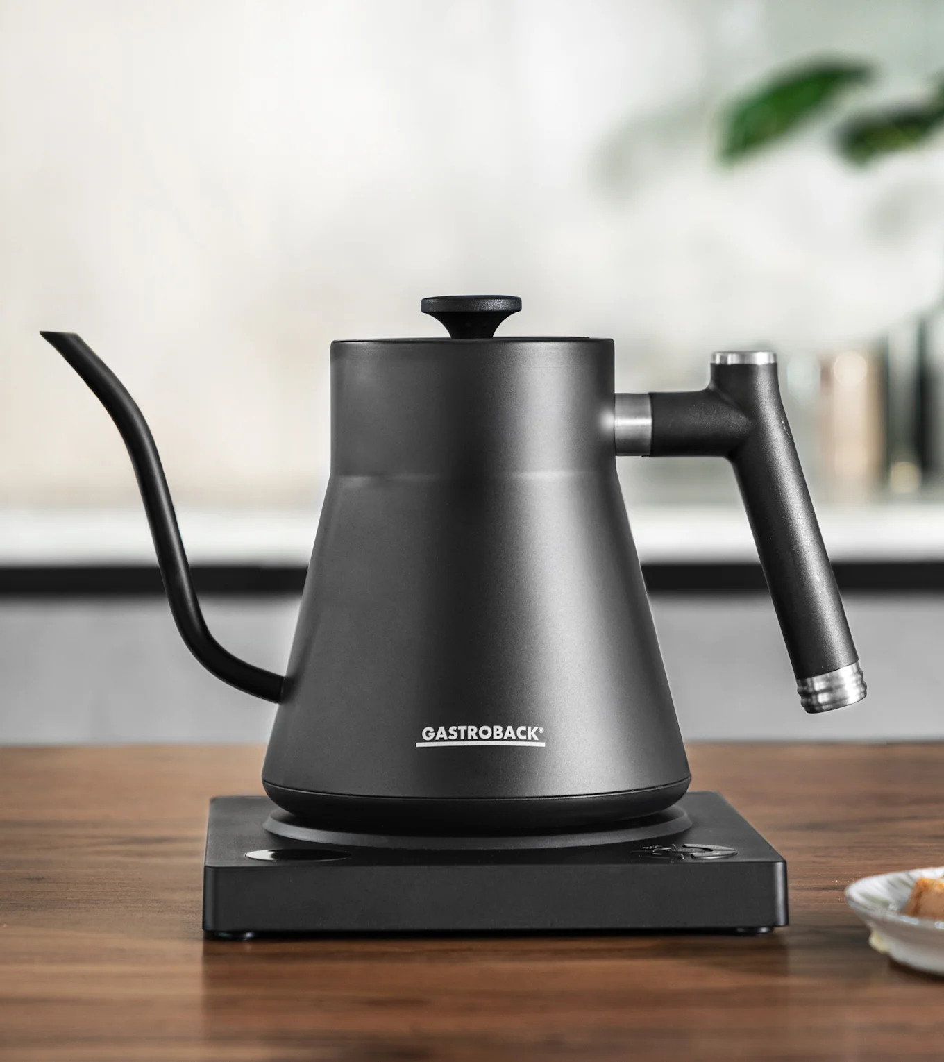 Mattschwarzer Pour-over-Wasserkocher mit Schwanenhalsauslauf auf passendem Elektro-Sockel.