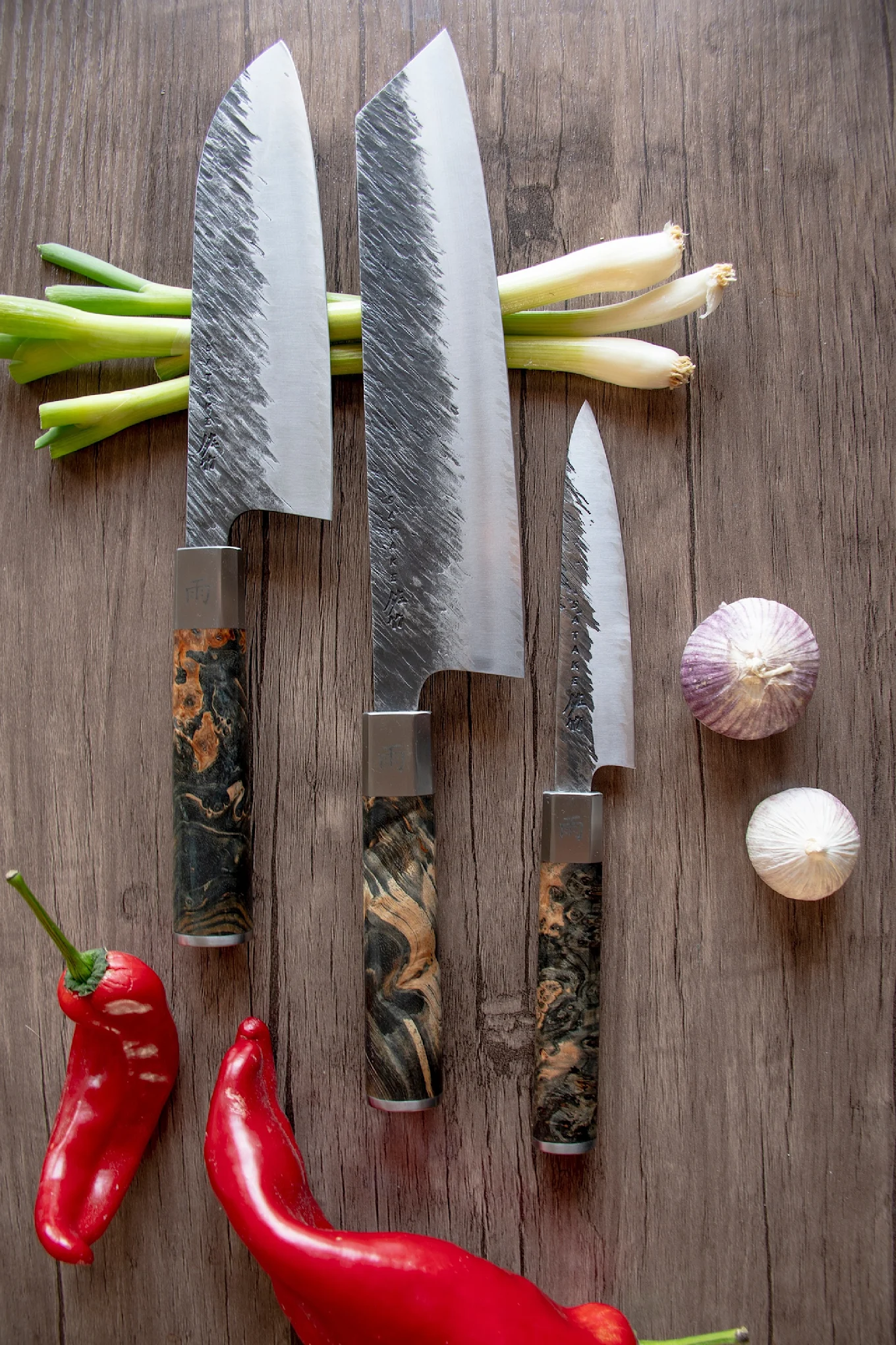 Drei japanische Messer aus dem Ame Messerset von Satake auf einem Schneidebrett.