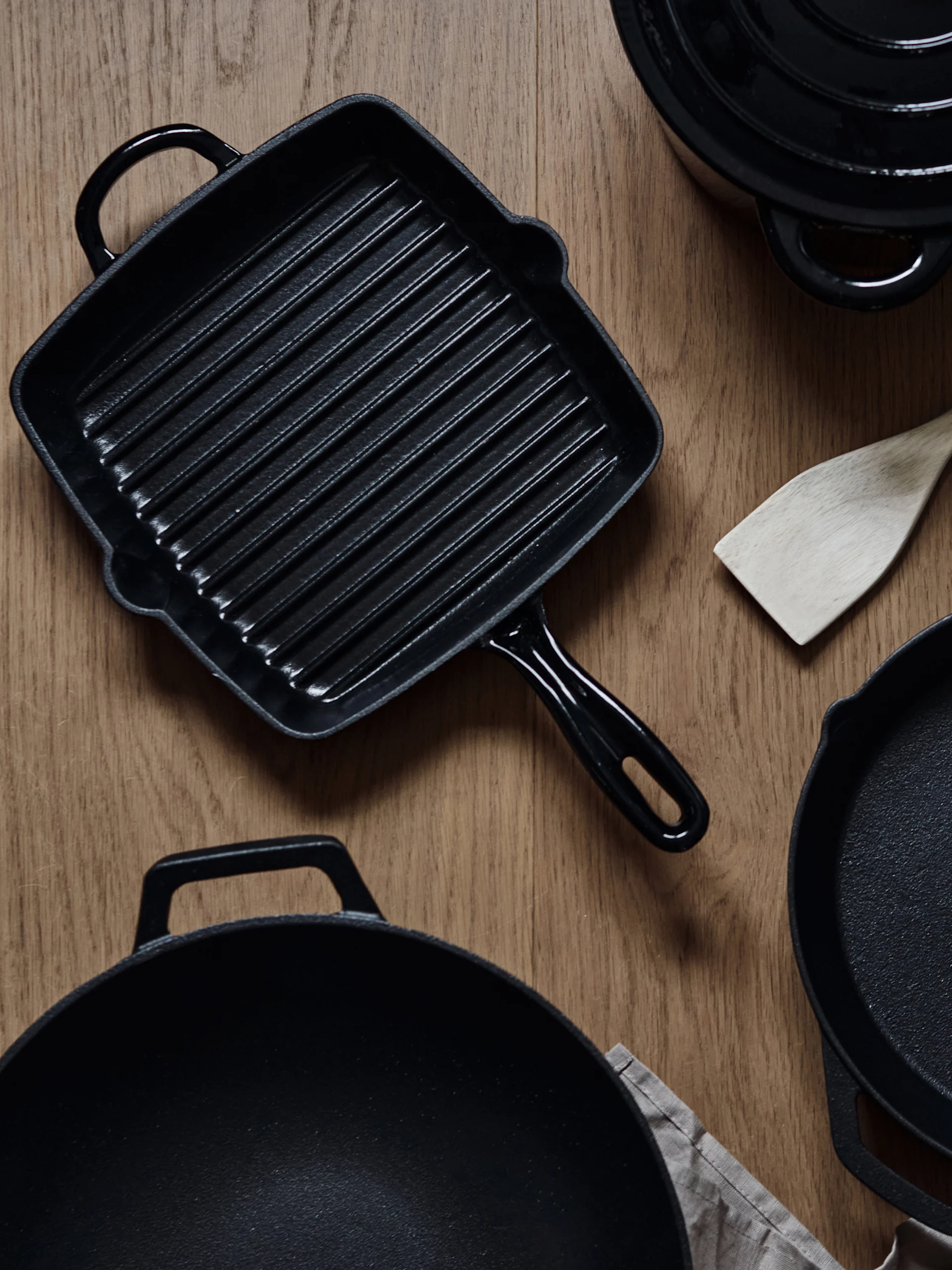 Gusseisenpfanne einbrennen und reinigen: Die Grillpfanne und der Wok von Nordwik stehen auf einem Tisch.