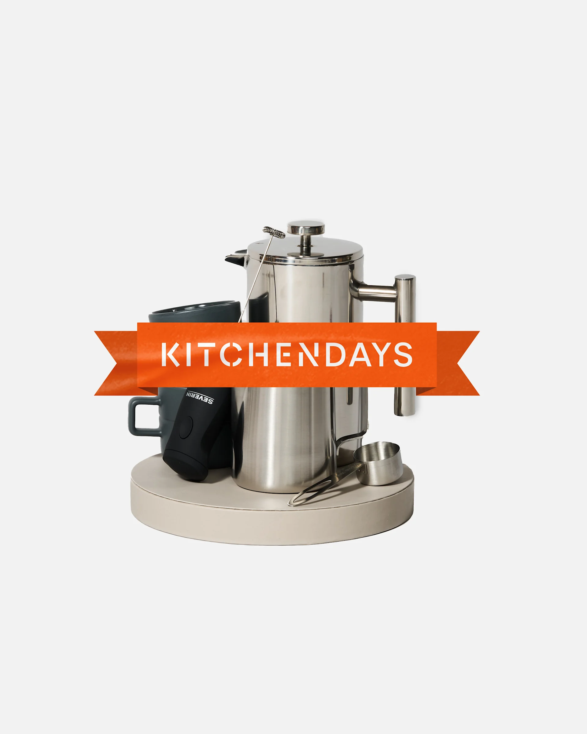 Küchenset: Edelstahl-French Press, dunkle Tassen, Milchaufschäumer, Messlöffel auf Tablett. 'KITCHENDAYS'-Banner.