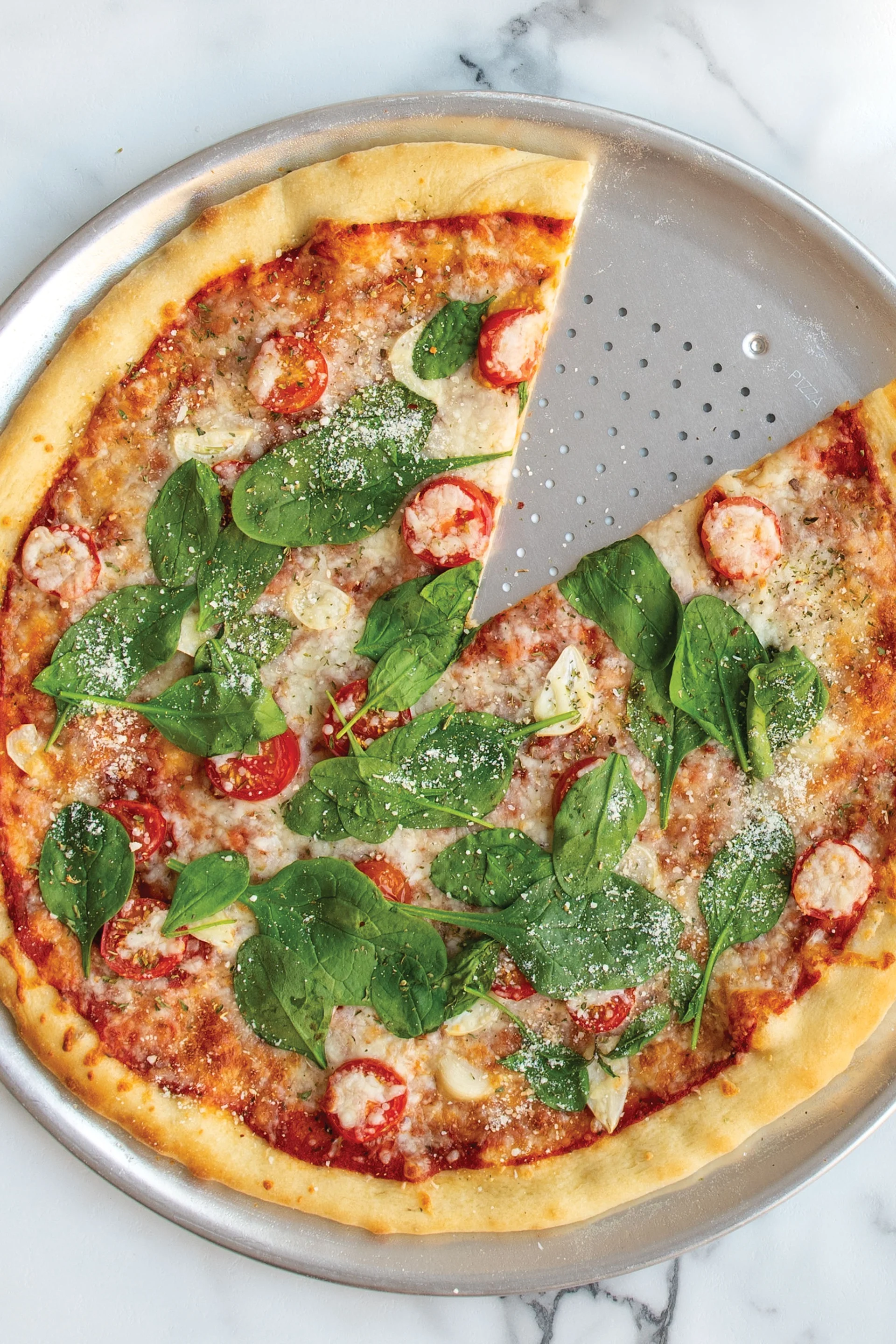 Mithilfe von Ersatzprodukten lässt sich eine Pizza ganz unkompliziert vegan machen. Um einen möglichst knusperigen Boden zu erzielen, eignet sich das perforierte Pizzablech von Nordic Ware hervorragend.