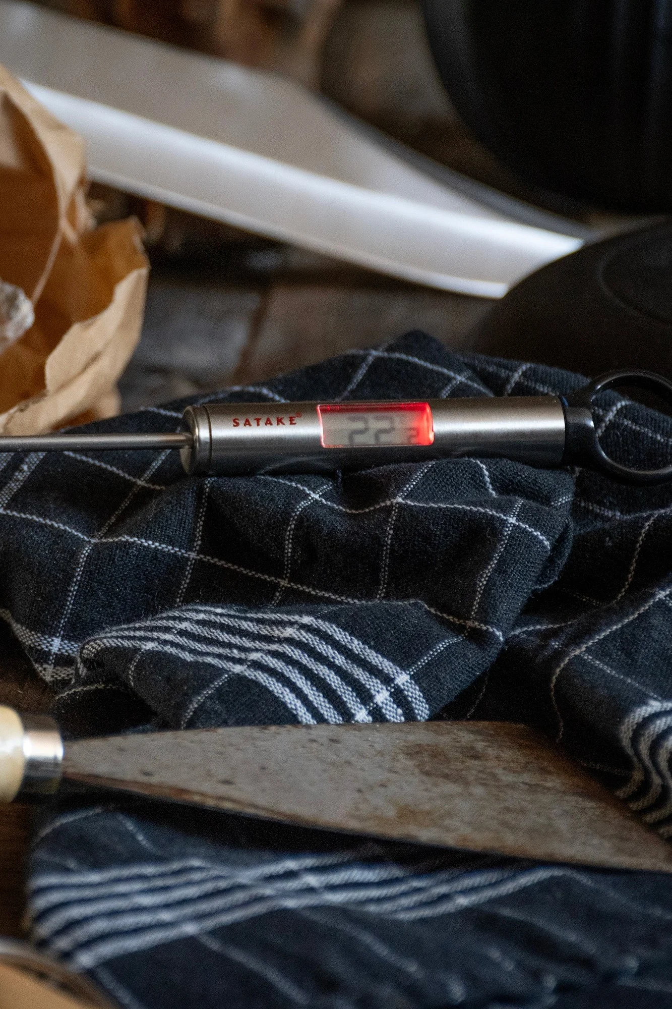 Das digitale Thermometer von Satake liegt auf einem Küchentuch vor einer Schale mit Brötchen.