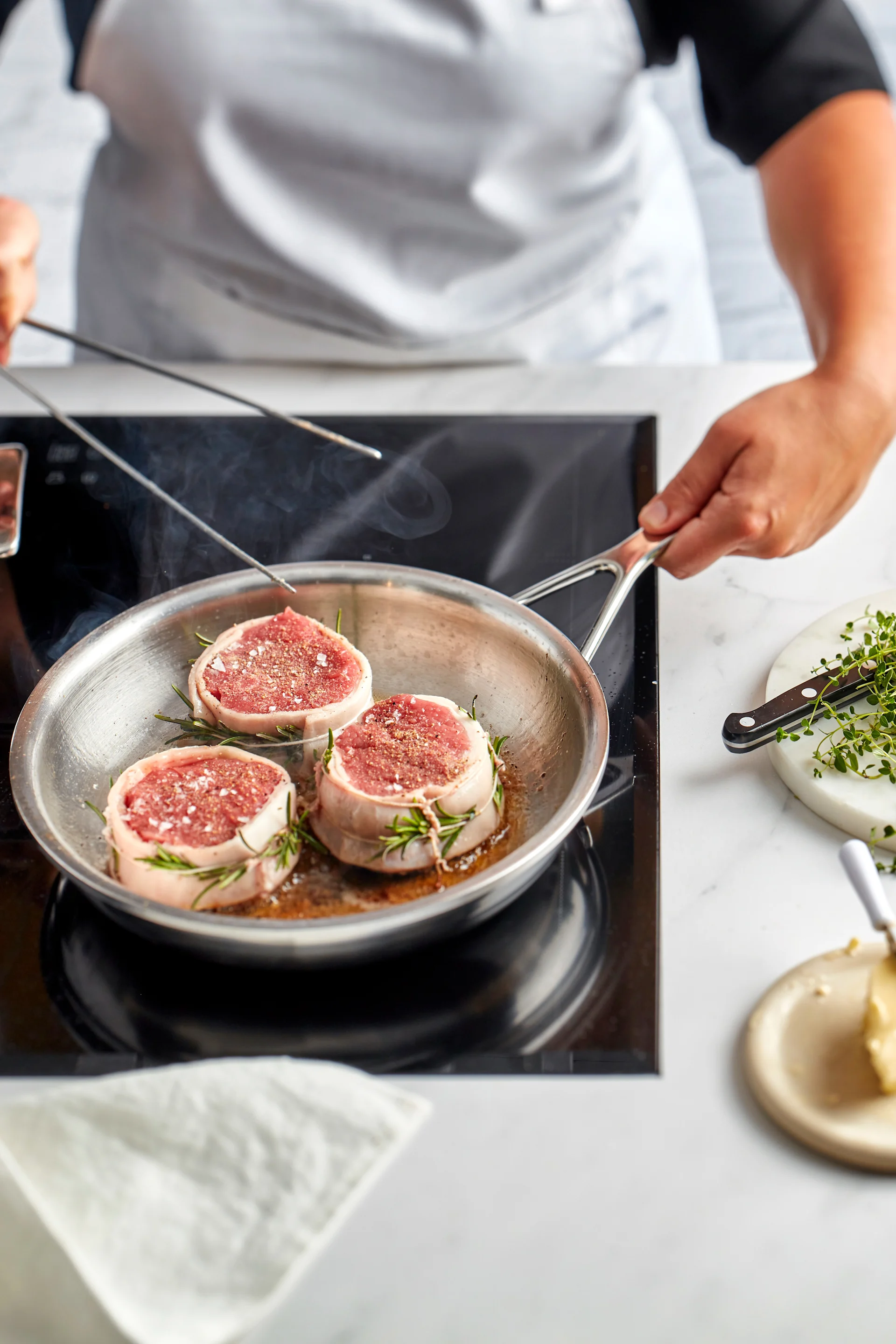 Umwickeln Sie Schweinefilet mit Speck und Rosmarin und braten Sie die Medaillons in der Vitality Pfanne von Zwilling scharf an.